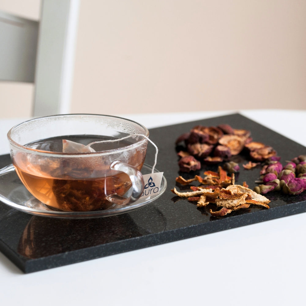 A herbal tea on a black slab alongside some traditional Chinese herbs.